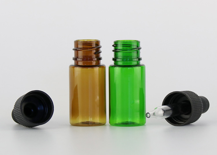 Las pequeñas botellas de aceite esencial vacías de cristal alisan la superficie con el dropper plástico